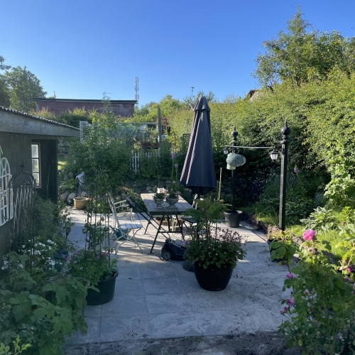 Nyanlagt fliseterrasse i Ellinge, mellem Nyborg og Odense, med havemøbler og blomsterkrukker.