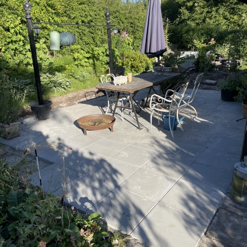 Terrasse med fliser i Ellinge på Fyn, omgivet af planter.