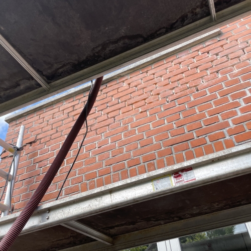 Nærbillede af stillads og murværk under facaderenovering i Odense.