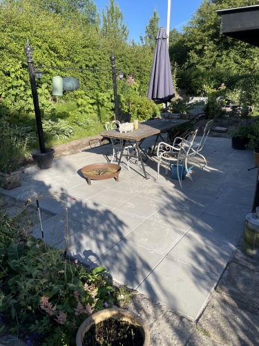 Terrasse med fliser i Ellinge på Fyn, omgivet af planter.