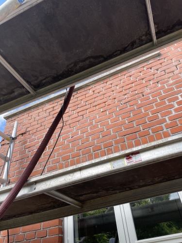 Nærbillede af stillads og murværk under facaderenovering i Odense.