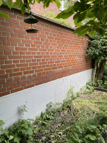 Renoveret murværk med nye fuger i Odense efter facaderenovering på lav del af væg.